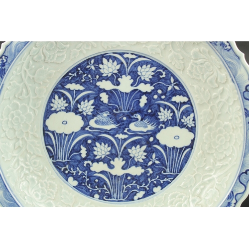 611 - A CHINESE BLUE AND WHITE CARVED FLORAL CHARGER. 44cms diameter.