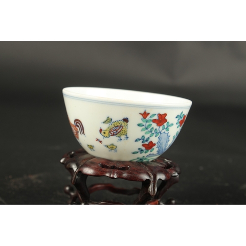 620 - A CHINESE WUCAI CHICKEN TEA CUP on a wooden stand. Cup: 8cms diameter.