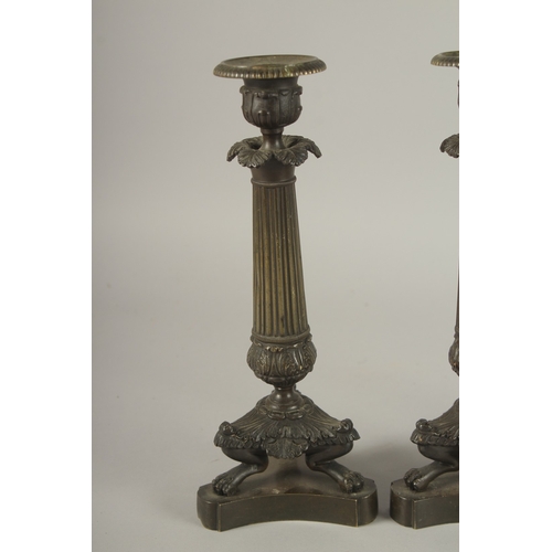 719 - A GOOD SET OF FOUR REGENCY BRONZE CANDLESTICKS with triangular bases and claw feet. 10ins high.