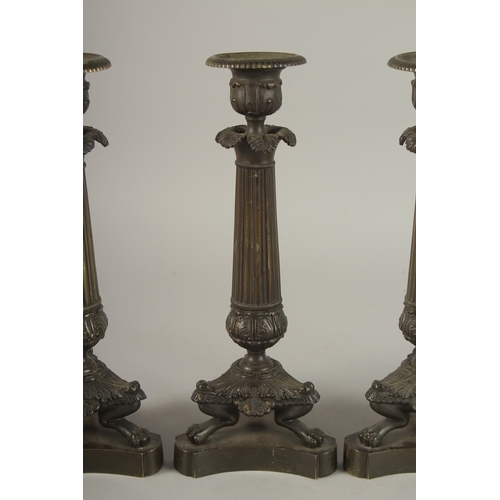 719 - A GOOD SET OF FOUR REGENCY BRONZE CANDLESTICKS with triangular bases and claw feet. 10ins high.