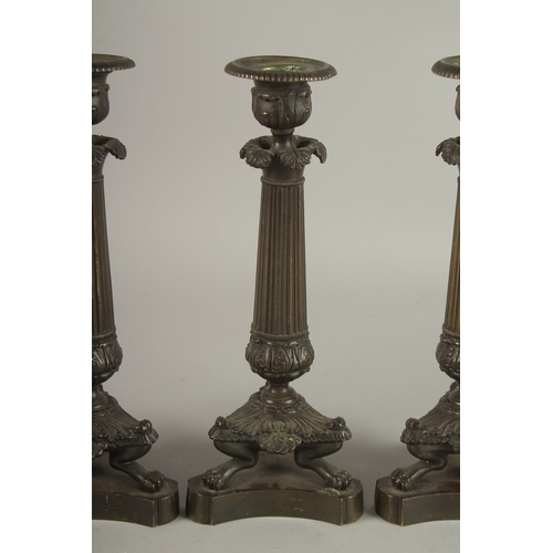 719 - A GOOD SET OF FOUR REGENCY BRONZE CANDLESTICKS with triangular bases and claw feet. 10ins high.