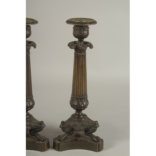 719 - A GOOD SET OF FOUR REGENCY BRONZE CANDLESTICKS with triangular bases and claw feet. 10ins high.