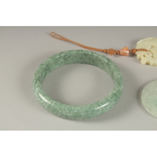 10 - THREE CARVED JADE PENDANTS, one with gold clasp, together with a green hardstone bangle, (4).