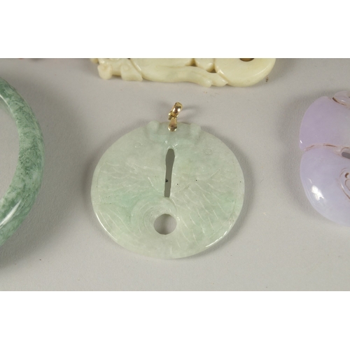 10 - THREE CARVED JADE PENDANTS, one with gold clasp, together with a green hardstone bangle, (4).