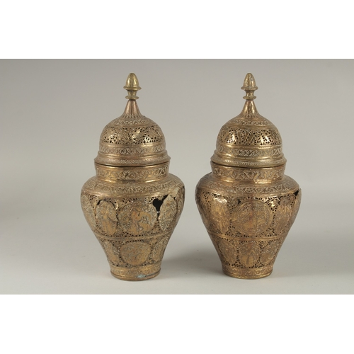 200 - A PAIR OF PERSIAN QAJAR OPENWORKED LIDDED BRASS JARS, decorated with figures and floral motifs, 28cm... 