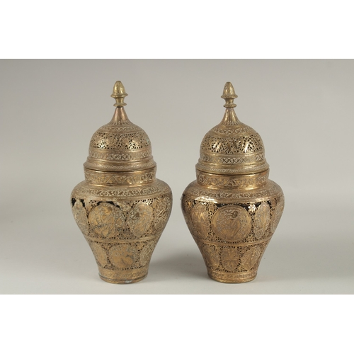 200 - A PAIR OF PERSIAN QAJAR OPENWORKED LIDDED BRASS JARS, decorated with figures and floral motifs, 28cm... 