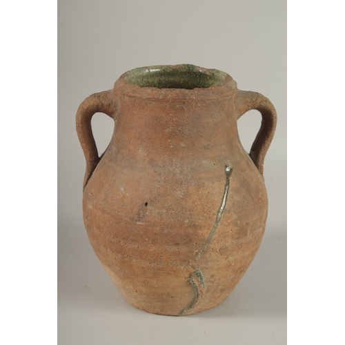 204 - A 10TH CENTURY MIDDLE EASTERN UNGLAZED POTTERY TWIN HANDLE JUG, the interior with traces of green gl... 