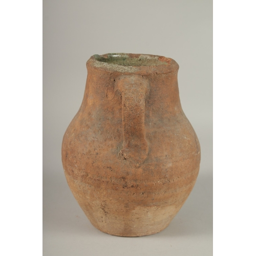 204 - A 10TH CENTURY MIDDLE EASTERN UNGLAZED POTTERY TWIN HANDLE JUG, the interior with traces of green gl... 