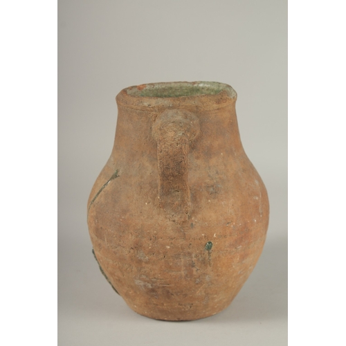 204 - A 10TH CENTURY MIDDLE EASTERN UNGLAZED POTTERY TWIN HANDLE JUG, the interior with traces of green gl... 