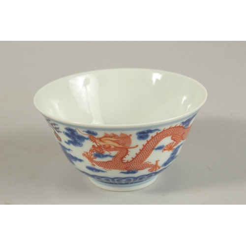 306 - A CHINESE BLUE AND WHITE WITH COPPER RED DRAGON TEA BOWL, six-character mark to base, 11cm diameter.