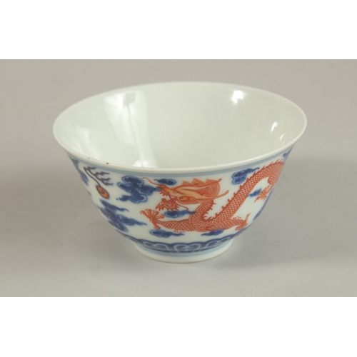 306 - A CHINESE BLUE AND WHITE WITH COPPER RED DRAGON TEA BOWL, six-character mark to base, 11cm diameter.