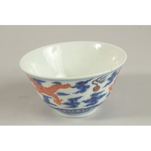 306 - A CHINESE BLUE AND WHITE WITH COPPER RED DRAGON TEA BOWL, six-character mark to base, 11cm diameter.