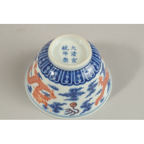 306 - A CHINESE BLUE AND WHITE WITH COPPER RED DRAGON TEA BOWL, six-character mark to base, 11cm diameter.