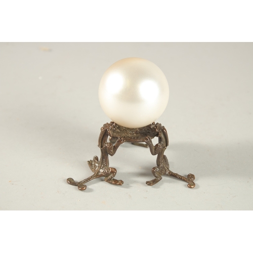 312 - A PEARLESCENT SPHERICAL ORNAMENT ON A BRONZE STAND, the stand formed with tripod chilong legs.