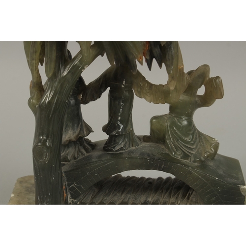 48 - A LARGE CHINESE CARVED JADE GROUP, depicting three figures on a bridge beneath a tree, together with... 