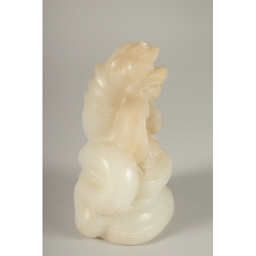 50 - A CARVED ALABASTER BUDDHISTIC FIGURE, with seated buddha and overarching dragon, 14cm high.