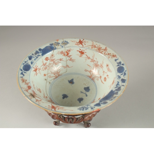 57 - A CHINESE PORCELAIN BOWL AND HARDWOOD STAND, (af), 19cm diameter.