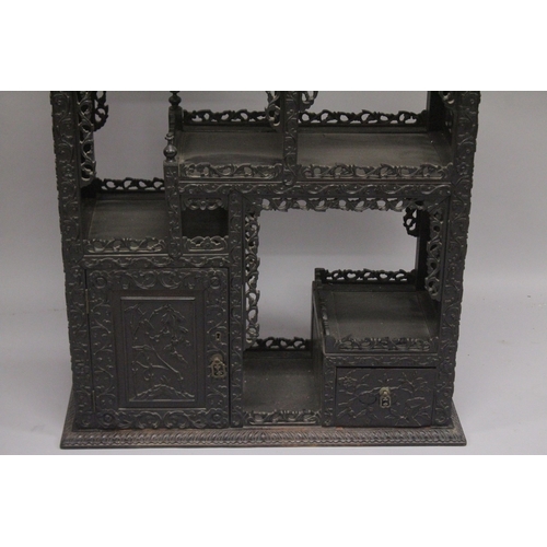 82 - A FINE CHINESE CARVED OPENWORK HARDWOOD DISPLAY CABINET, 154cm high, 8cm wide, 36cm deep.