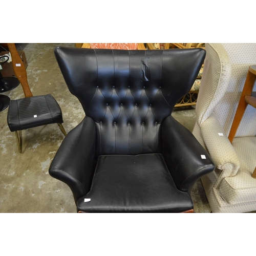 168 - A stylish black vinyl revolving wing armchair with matching stool in the manner of Eames.