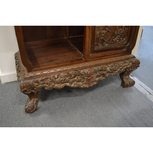 323 - A late 19th century carved hardwood display cabinet with two decoratively carved panel doors, a call... 