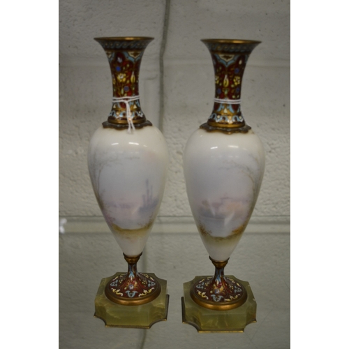 600 - A pair of porcelain, champleve enamel and onyx pedestal vases, each decorated with a figure.