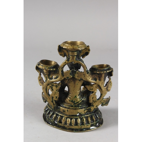 110 - A FINE 17TH CENTURY NEPALESE BRONZE OIL LAMP, with seated deity in the centre, 16cm high.