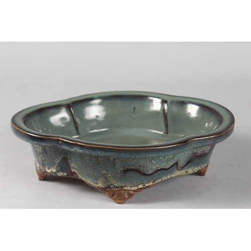 14 - A CHINESE FLAMBE GLAZED POTTERY QUATREFOIL FORM BOWL, raised on four feet, 24cm x 18.5cm.