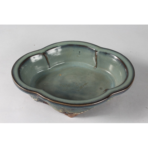 14 - A CHINESE FLAMBE GLAZED POTTERY QUATREFOIL FORM BOWL, raised on four feet, 24cm x 18.5cm.