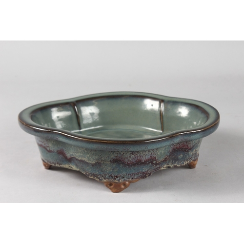 14 - A CHINESE FLAMBE GLAZED POTTERY QUATREFOIL FORM BOWL, raised on four feet, 24cm x 18.5cm.