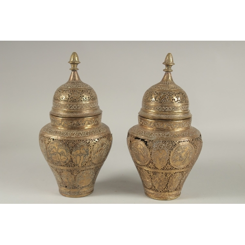 154 - A PAIR OF PERSIAN QAJAR OPENWORKED LIDDED BRASS JARS, decorated with figures and floral motifs, 28cm... 