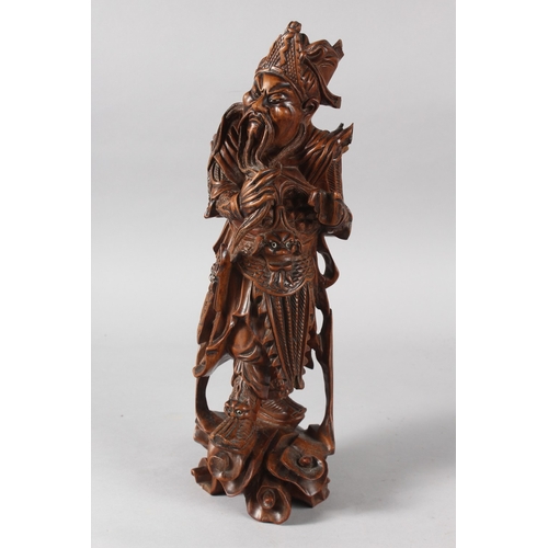 25 - A CHINESE CARVED HARDWOOD WARRIOR FIGURE, with multiple inset eyes, 39cm high.