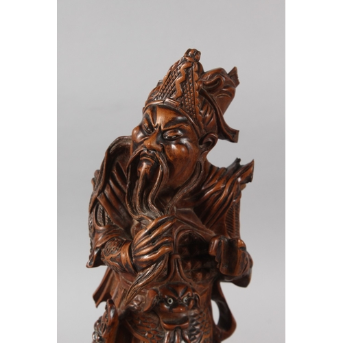 25 - A CHINESE CARVED HARDWOOD WARRIOR FIGURE, with multiple inset eyes, 39cm high.