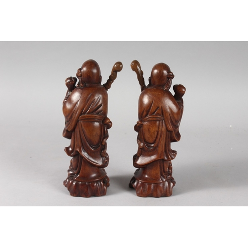 26 - A PAIR OF 19TH CENTURY CHINESE CARVED HARDWOOD FIGURES, with inset eyes and teeth, 21cm high.