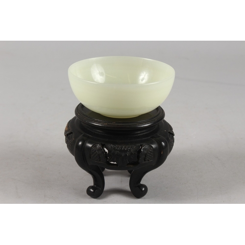 275 - A CHINESE JADE BOWL ON HARDWOOD STAND, bowl 10cm diameter.