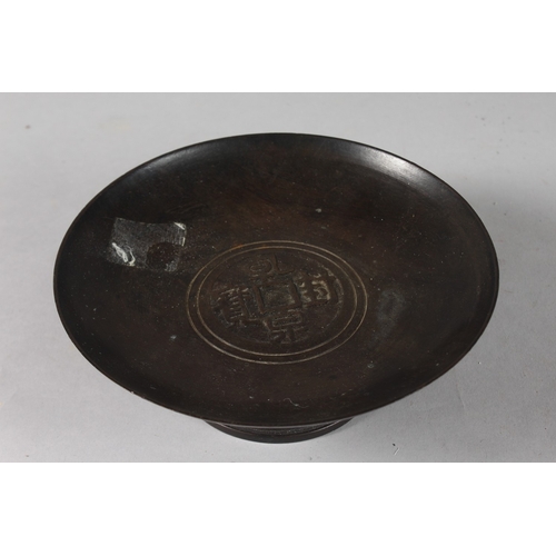 30 - A CHINESE BRONZE FOOTED CIRCULAR DISH, with central characters, 18cm diameter.