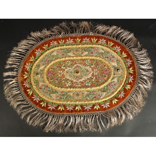 382 - AN INDIAN EMBROIDERED OVAL TEXTILE WITH VARIOUS INSET STONES.