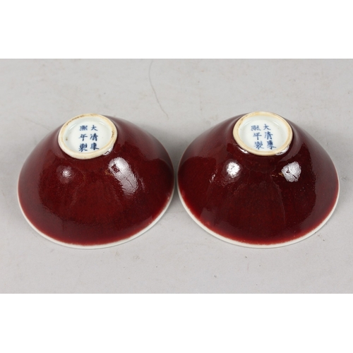 406 - A SMALL PAIR OF CHINESE RED GLAZED PORCELAIN BOWLS, each with six-character mark to base, 9cm diamet... 