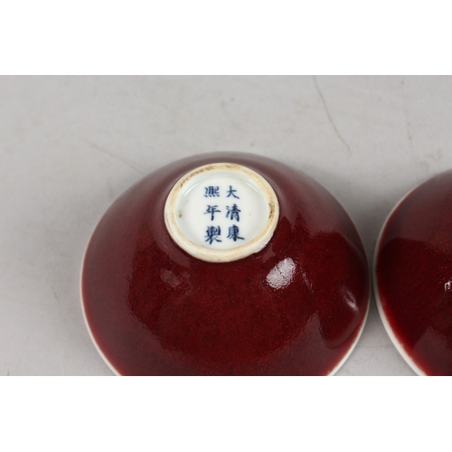 406 - A SMALL PAIR OF CHINESE RED GLAZED PORCELAIN BOWLS, each with six-character mark to base, 9cm diamet... 