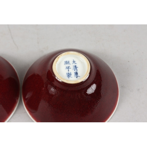 406 - A SMALL PAIR OF CHINESE RED GLAZED PORCELAIN BOWLS, each with six-character mark to base, 9cm diamet... 