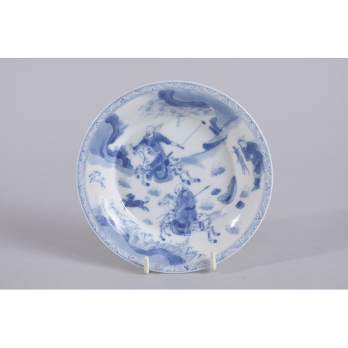 35 - A CHINESE KANGXI PERIOD BLUE AND WHITE PORCELAIN SAUCER, painted with a hunting scene, mark to base,... 