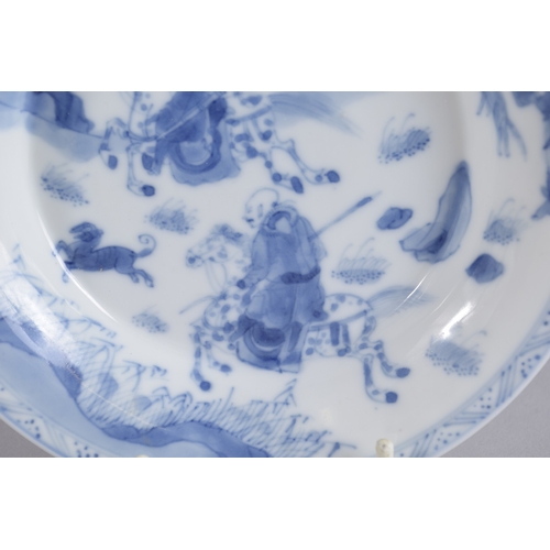 35 - A CHINESE KANGXI PERIOD BLUE AND WHITE PORCELAIN SAUCER, painted with a hunting scene, mark to base,... 