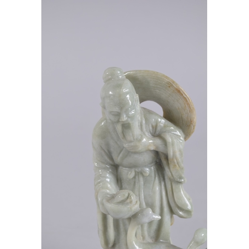 43 - A CHINESE CARVED JADEITE FIGURE ON HARDWOOD STAND, figure 13.5cm high.