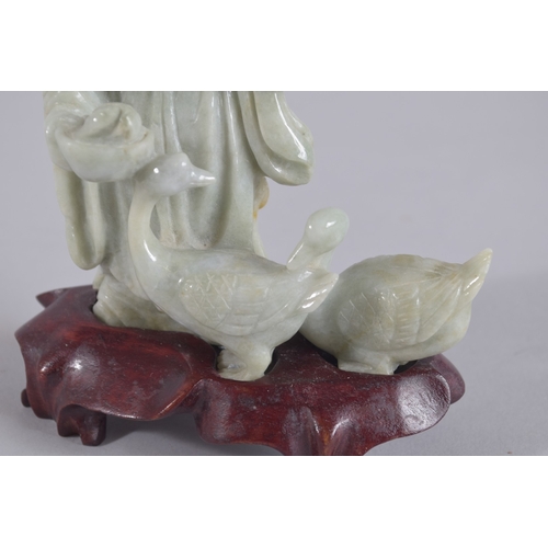 43 - A CHINESE CARVED JADEITE FIGURE ON HARDWOOD STAND, figure 13.5cm high.