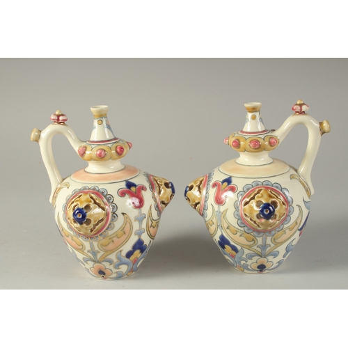 438 - A PAIR OF 19TH CENTURY ORIENTALIST HUNGARIAN ZSOLNAY PORCELAIN JUGS, 17cm high.