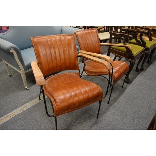 275 - A stylish pair of leather upholstered armchairs with wrought iron frames.