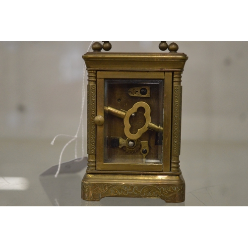 863 - A small brass carriage clock with porcelain dial and panels.