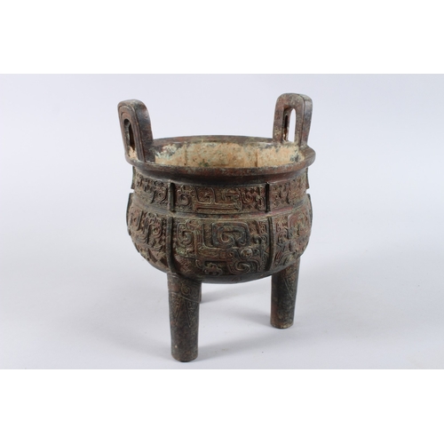 132 - AN ARCHAIC BRONZE CENSER with looped handles, on three legs. 8ins diameter.
