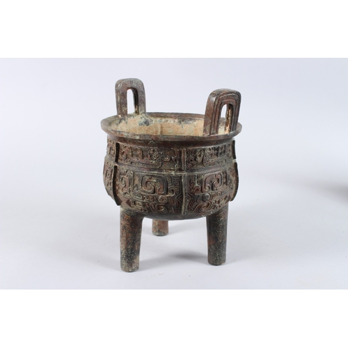 132 - AN ARCHAIC BRONZE CENSER with looped handles, on three legs. 8ins diameter.