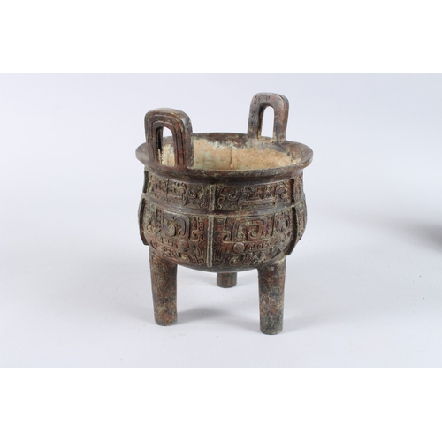 132 - AN ARCHAIC BRONZE CENSER with looped handles, on three legs. 8ins diameter.