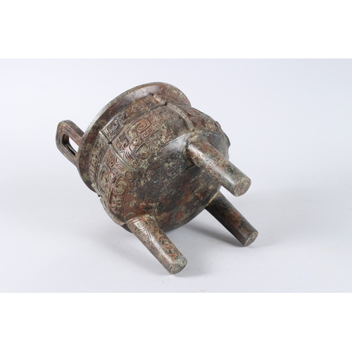 132 - AN ARCHAIC BRONZE CENSER with looped handles, on three legs. 8ins diameter.